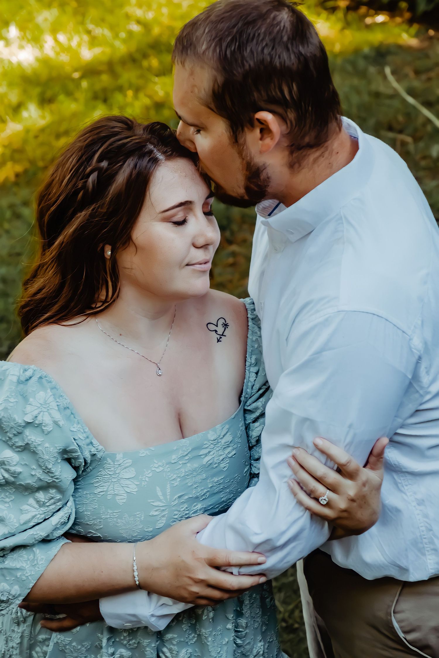 Romantic couple in soft natural lighting share an intimate moment outdoors, wearing white and mint blue clothing.