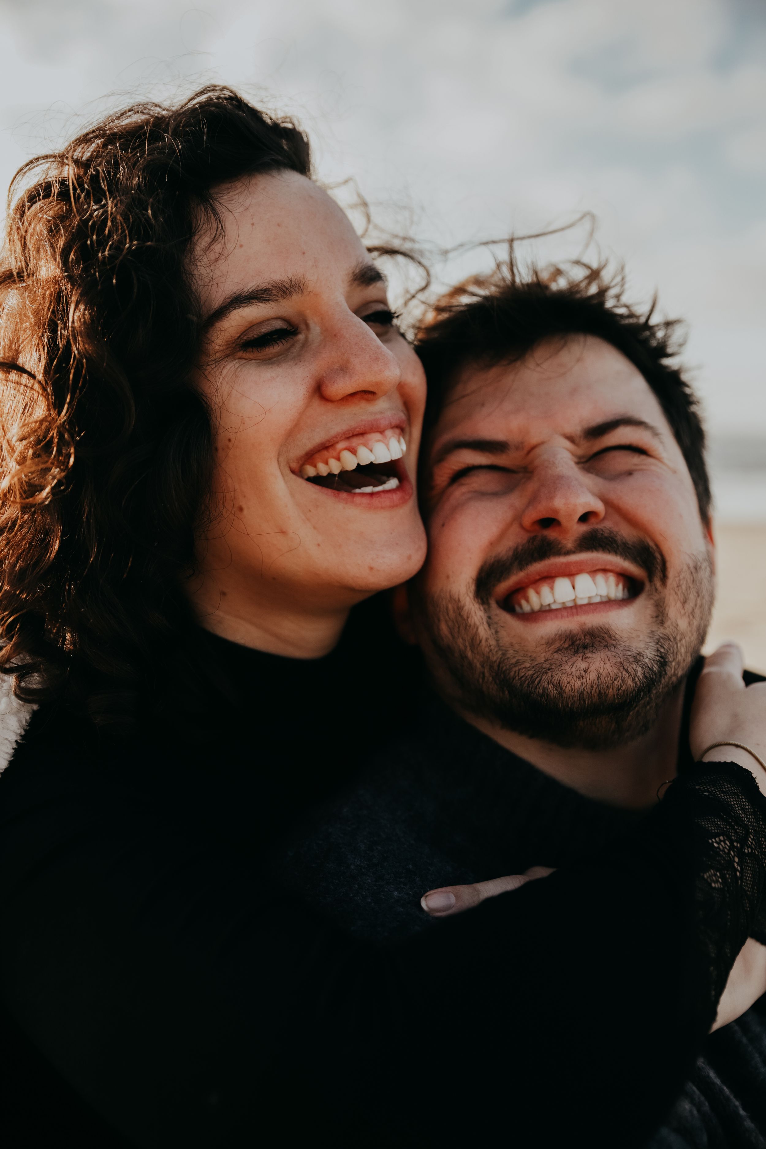 Joyful couple laughing together in close-up beach portrait.