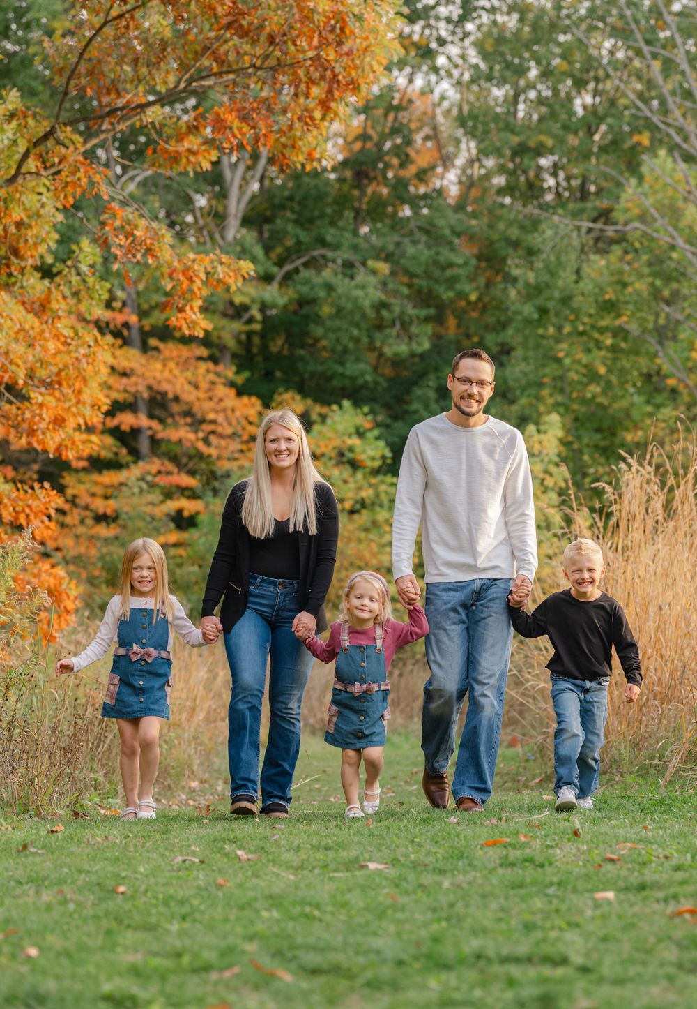 family walking holding hands on a path in the woods