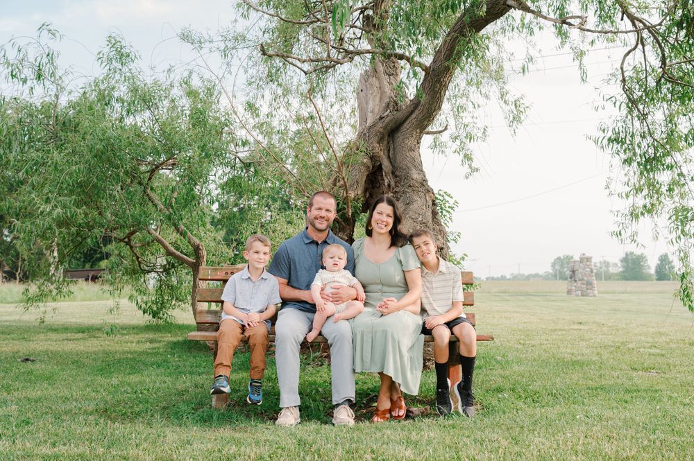 family sitting on bench in front of tree