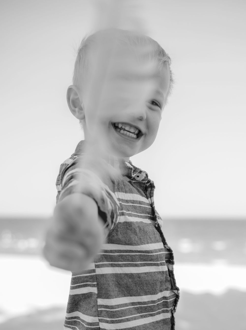 little boy showing off a feather he found in black and white