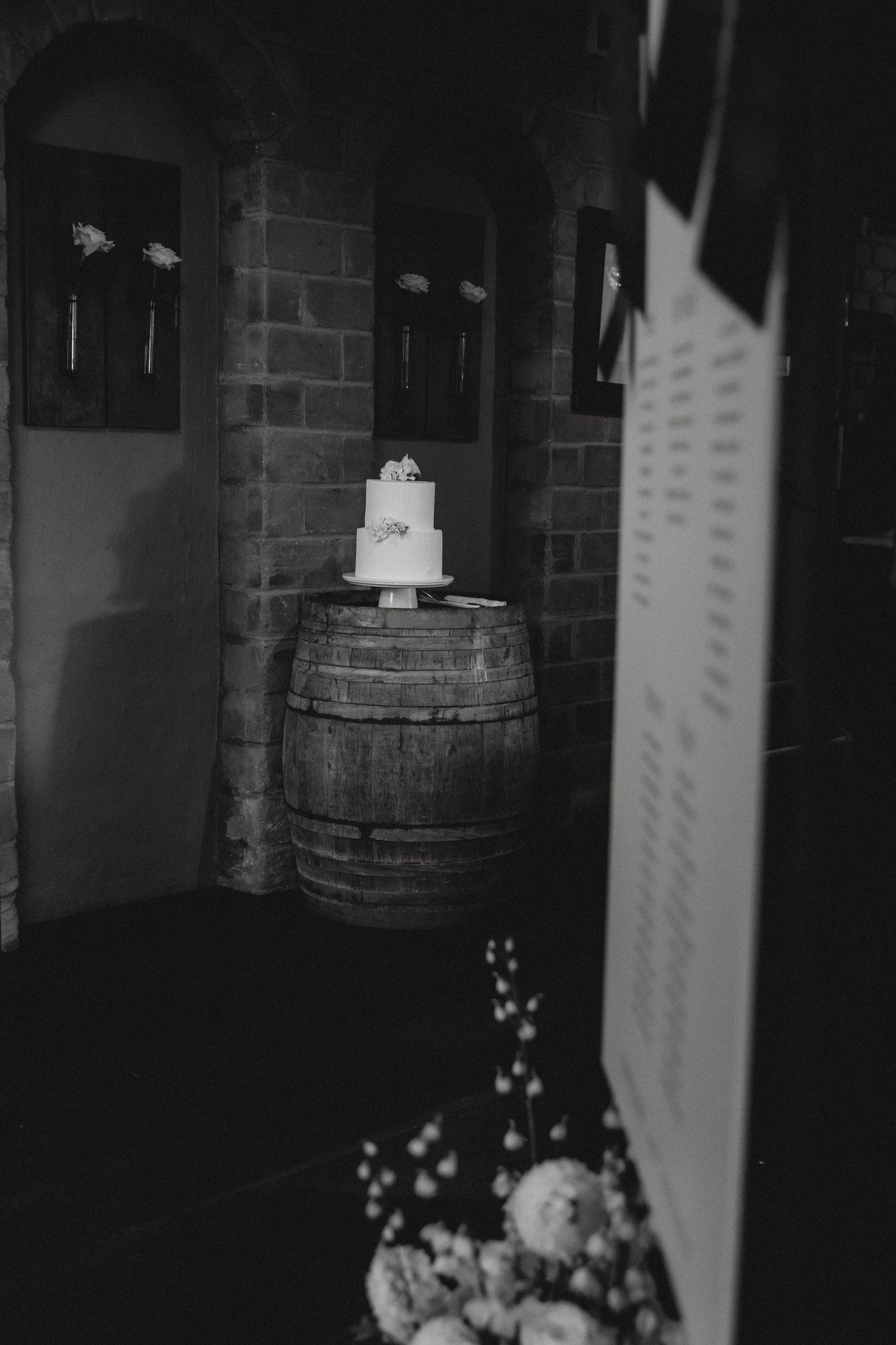 A row of wooden barrels displayed in a dimly lit cellar with brick walls and ambient lighting.