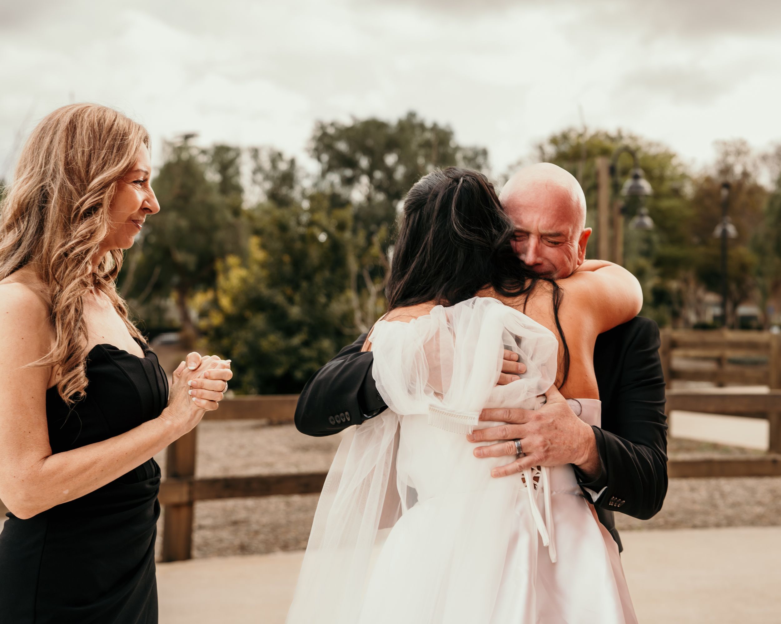 An emotional outdoor wedding moment captured at a rustic venue with warm autumn colors in the background.