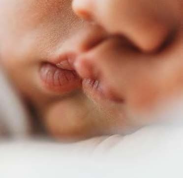 Close up of two people sharing an intimate romantic kiss in soft focus lighting.