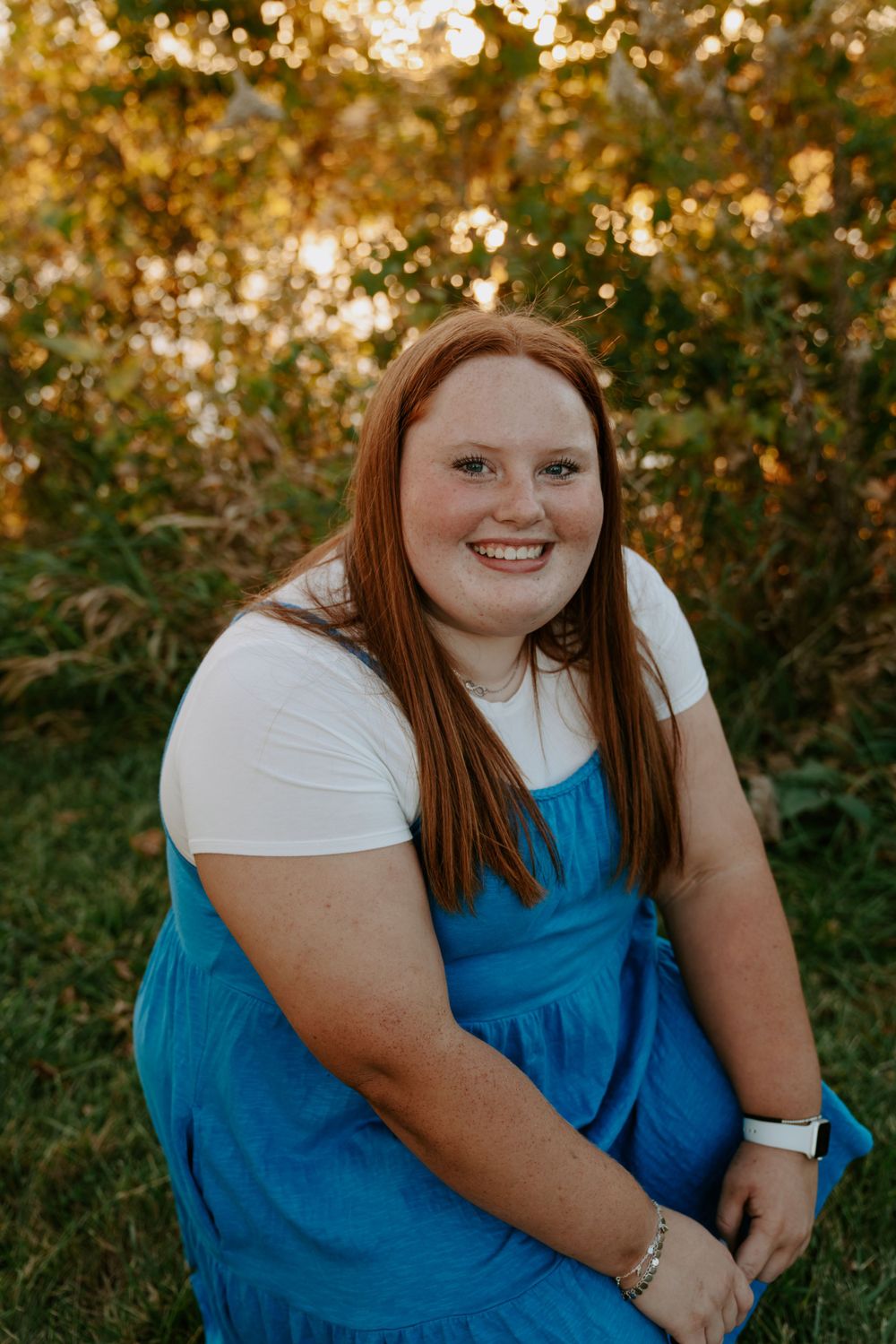 Outdoor portrait session in a natural setting with golden sunlight filtering through autumn foliage.