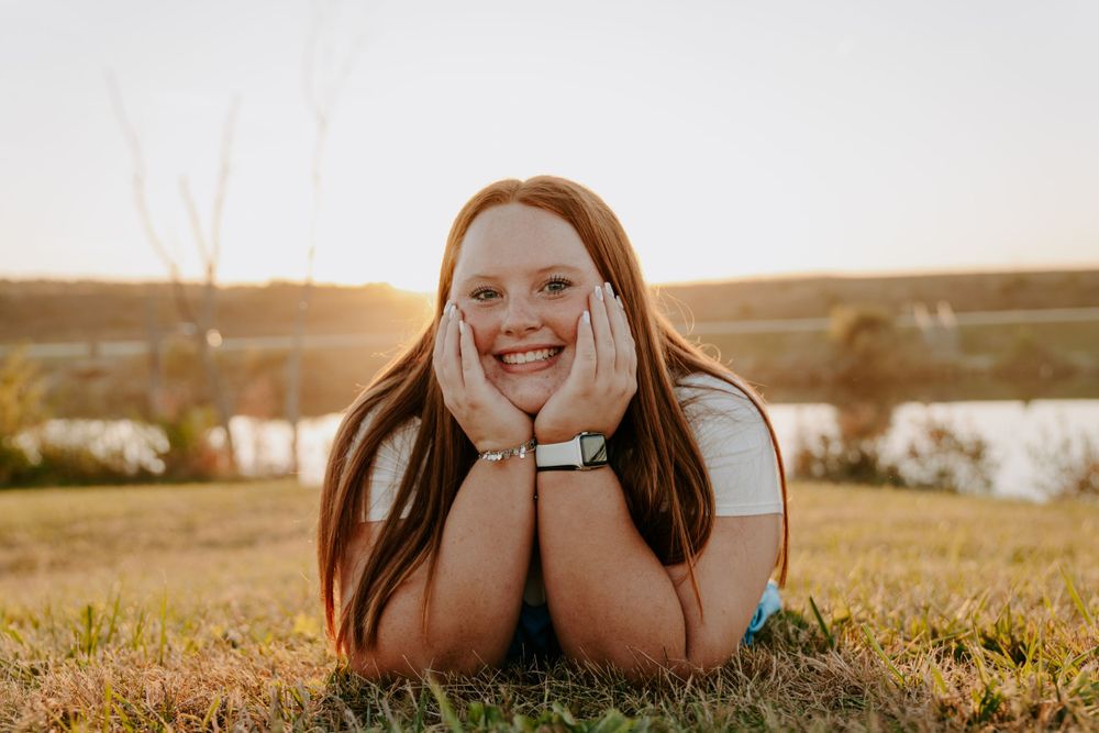 Playful outdoor portrait session with someone lying in grass during golden hour.
