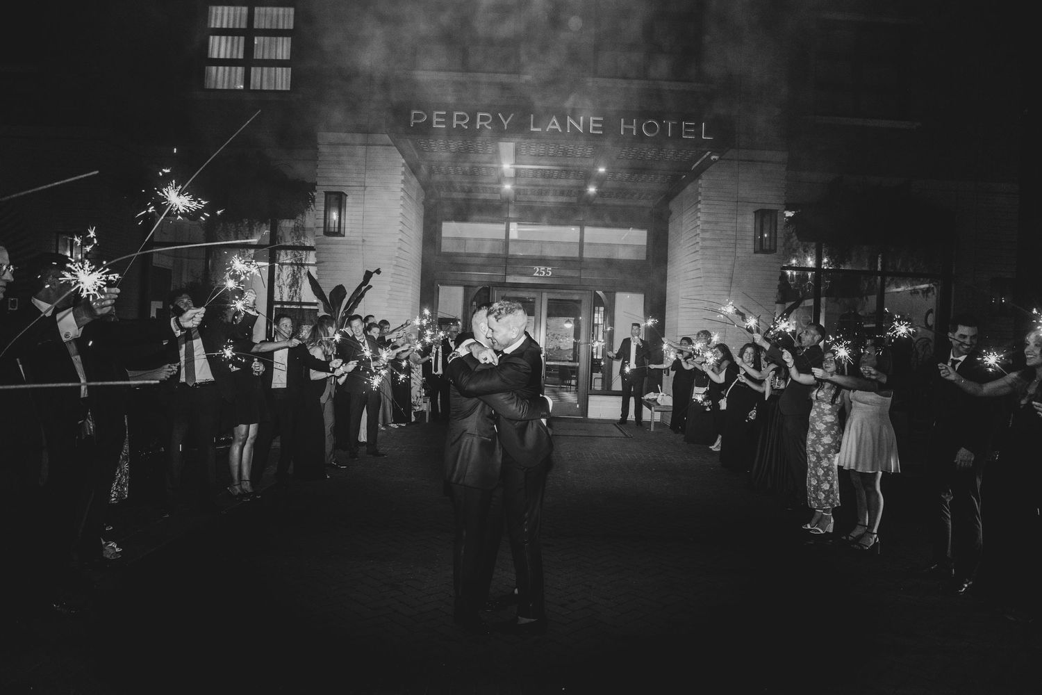 Black and white photo of couple sharing first dance outside Perry Lane Hotel with guests holding sparklers.