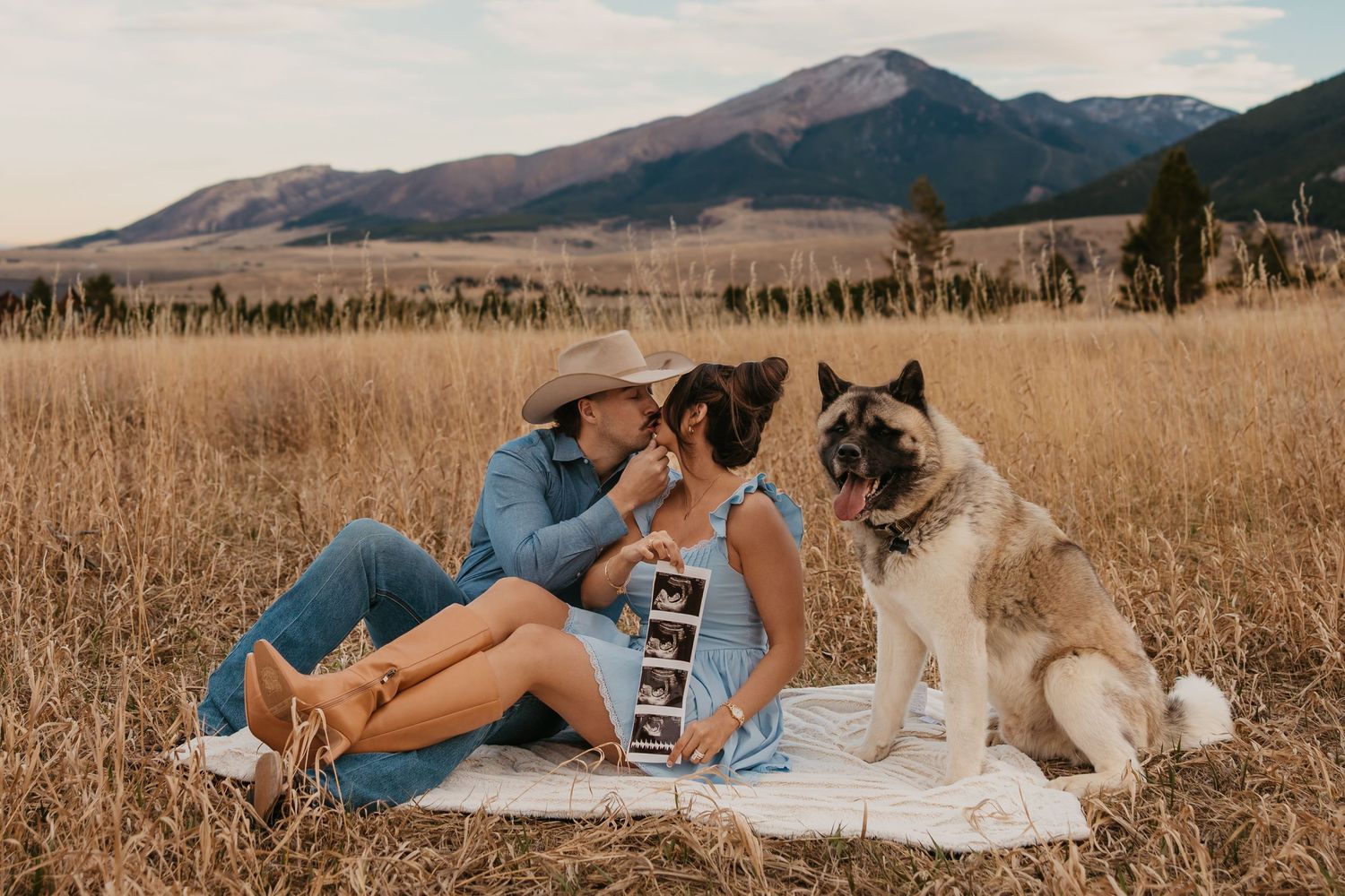 Couple cuddling shows off ultrasound photos with their dog in the mountains of Red Lodge, Montana captured by Montana Photographer