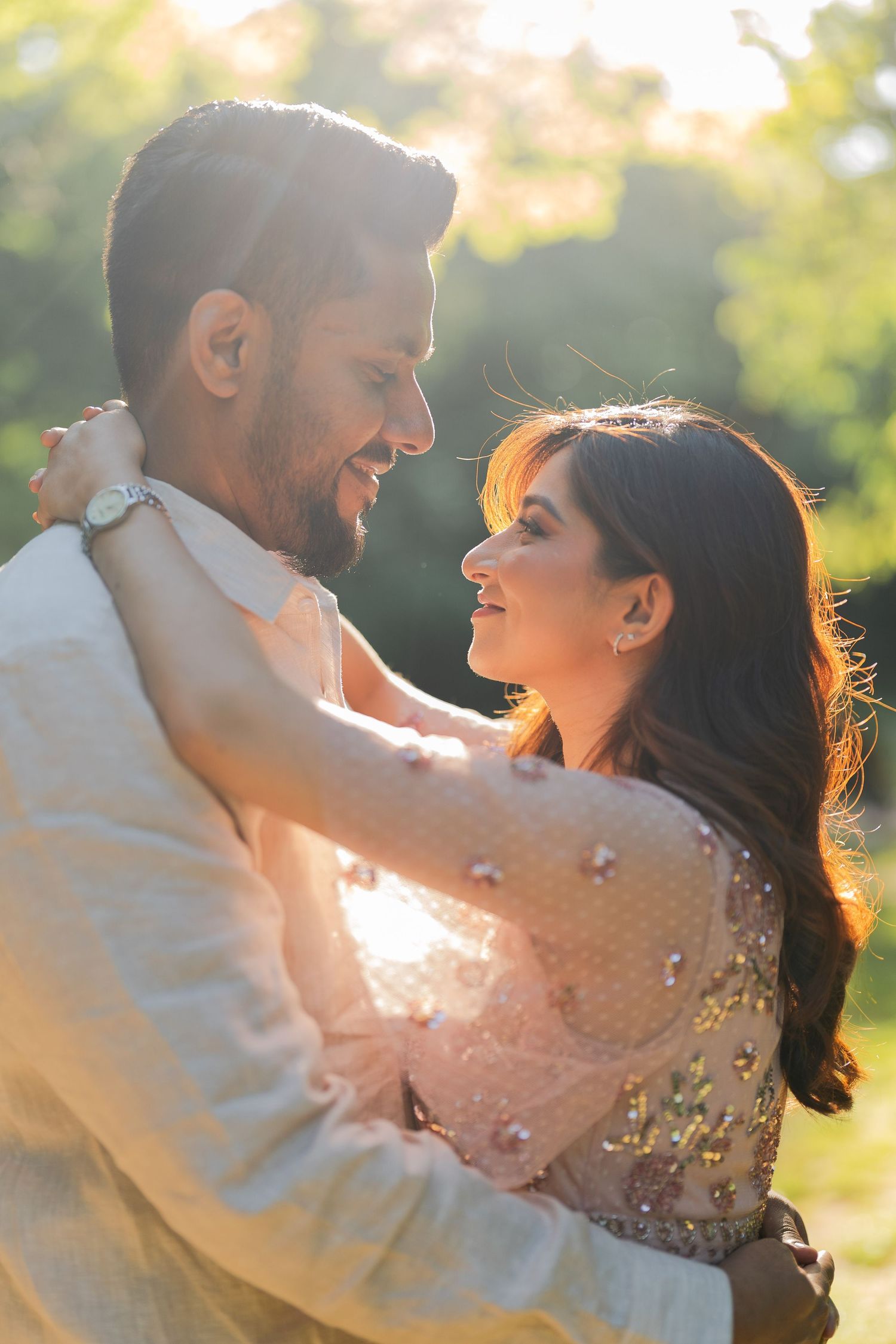 Man lifting woman in his arms during a golden sunset in a lush green park.