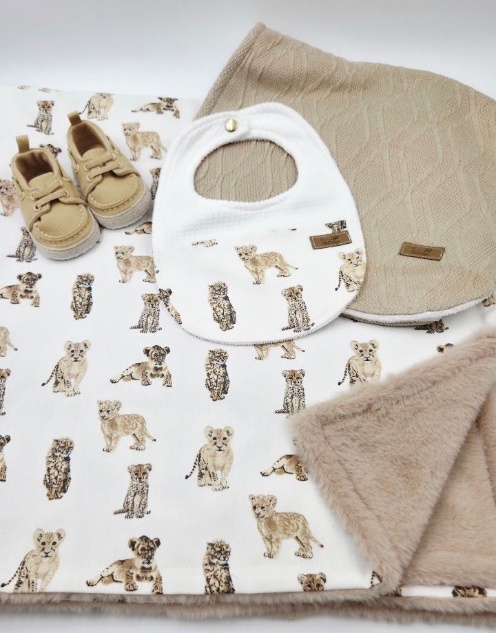Three white baby bibs with floral and gold dot prints displayed with tan leather infant sandals with ruffle detail.