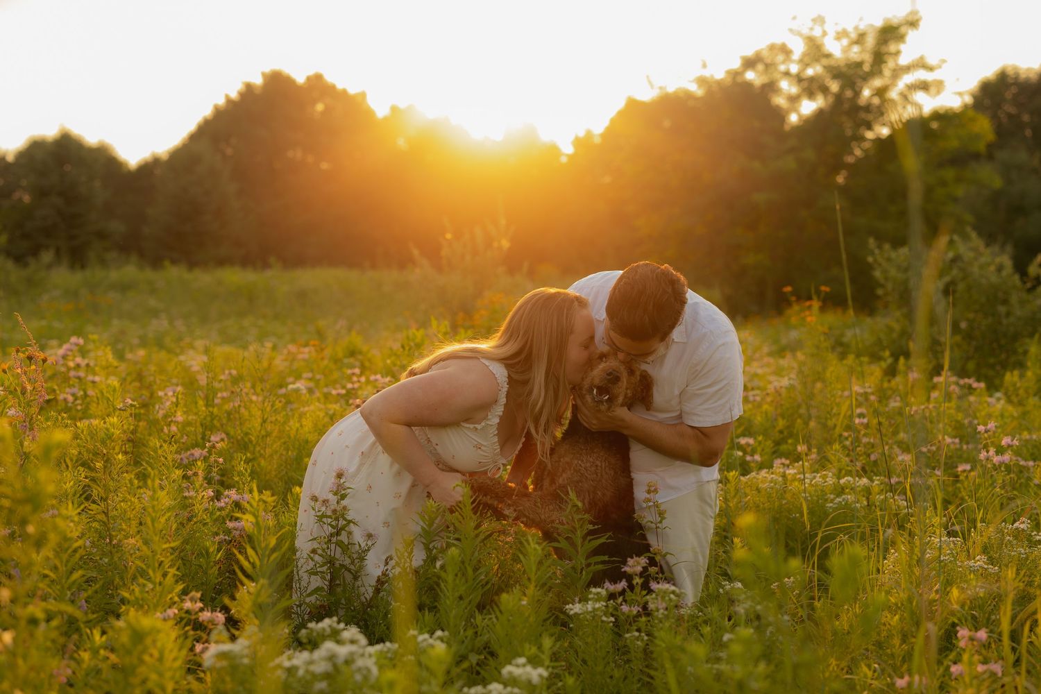 Couple sharing a tender moment in a sunlit wildflower field during golden hour sunset.