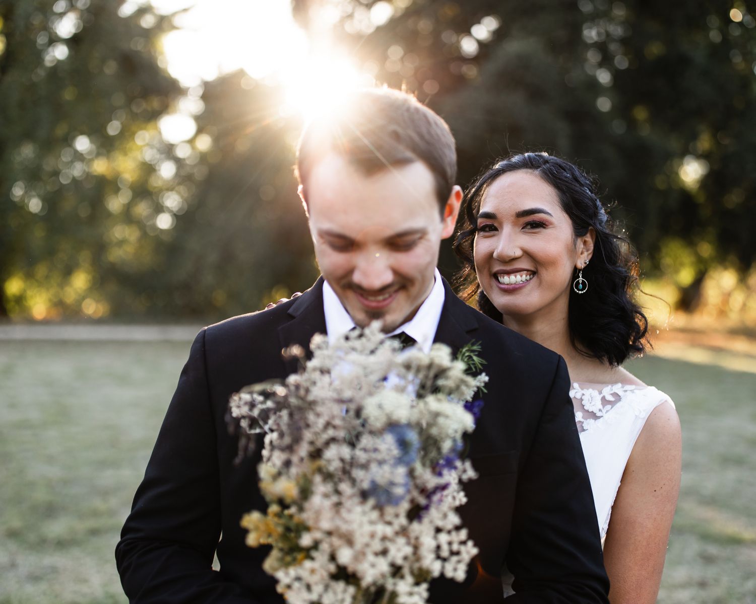 Black and white wedding photo of newlyweds sharing a joyful candid moment together with bokeh lights in background.