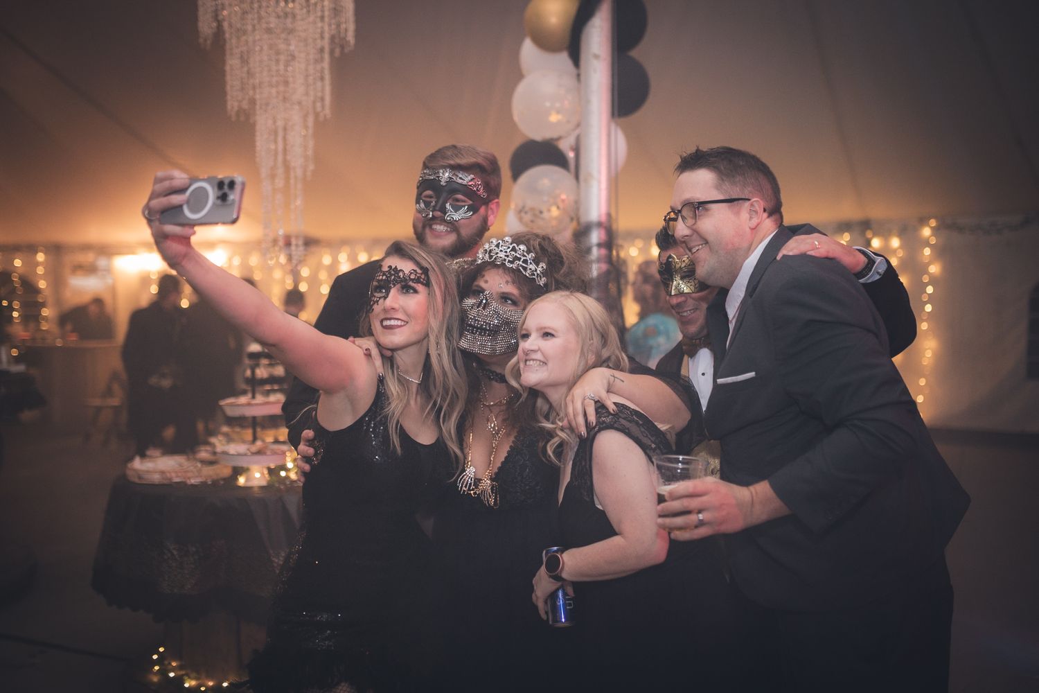 Women dancing with hands raised at a lively evening party or wedding reception in a dimly lit venue.