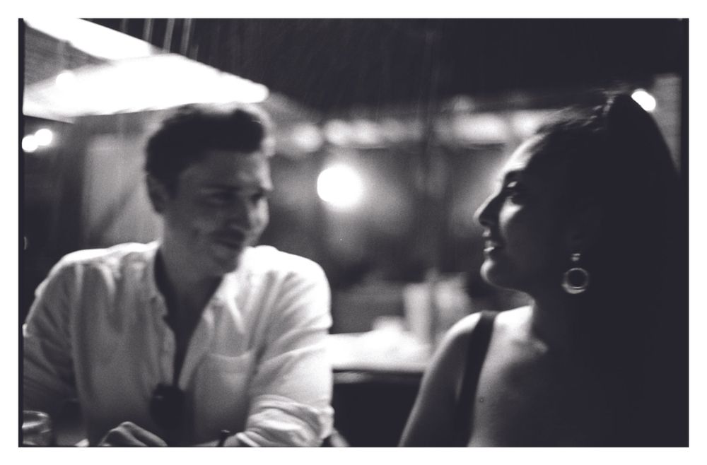 Intimate black and white photo of young man and woman sharing a moment in dim light.