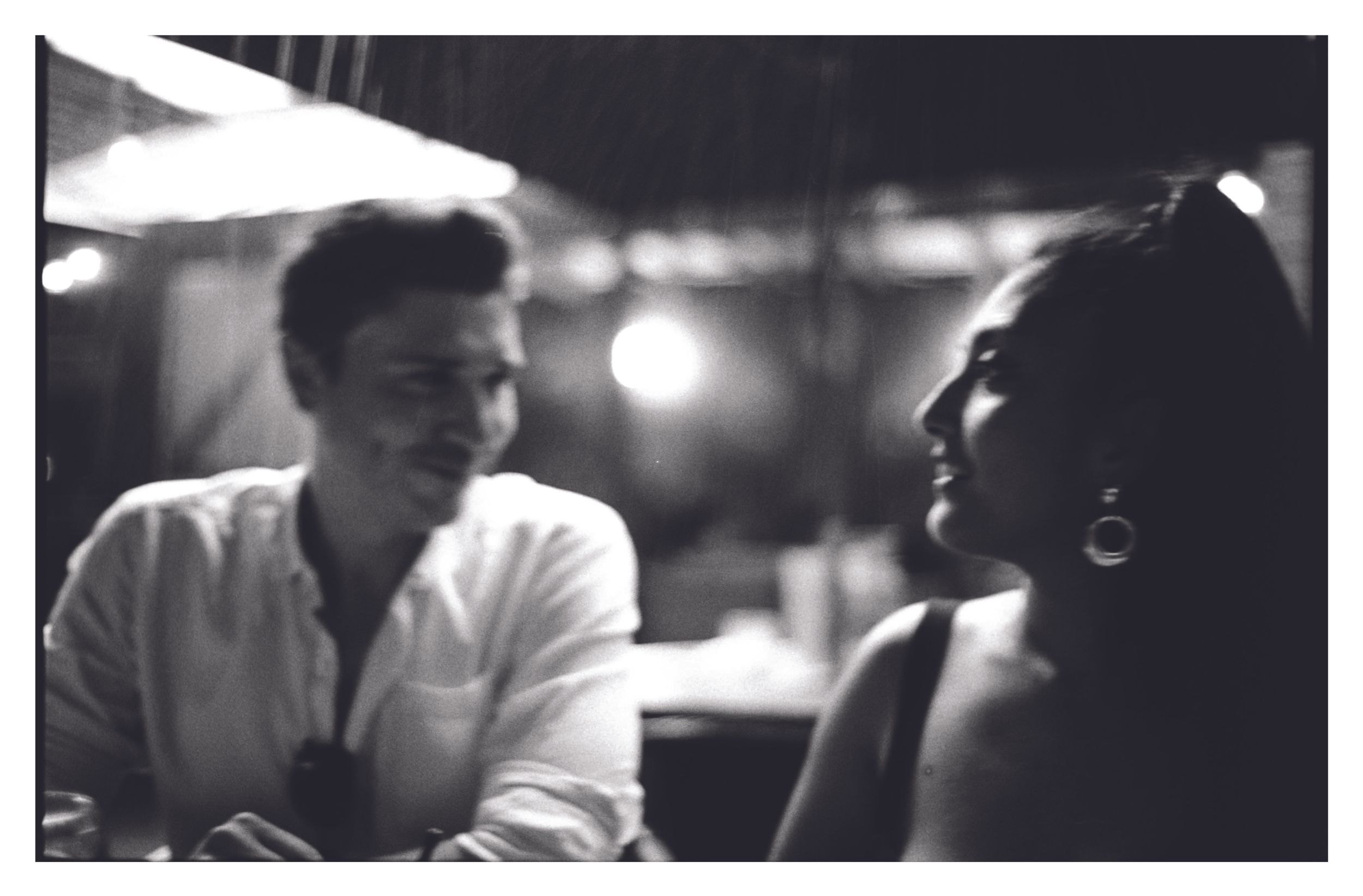 Intimate black and white photo of young man and woman sharing a moment in dim light.