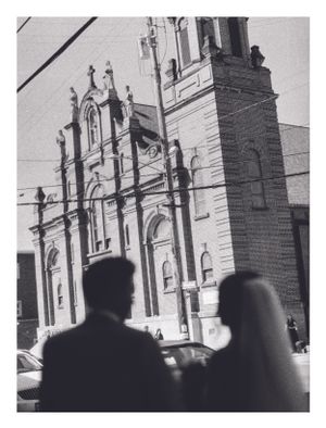 Black and white photo of a couple silhouetted before an ornate church facade on their wedding day.