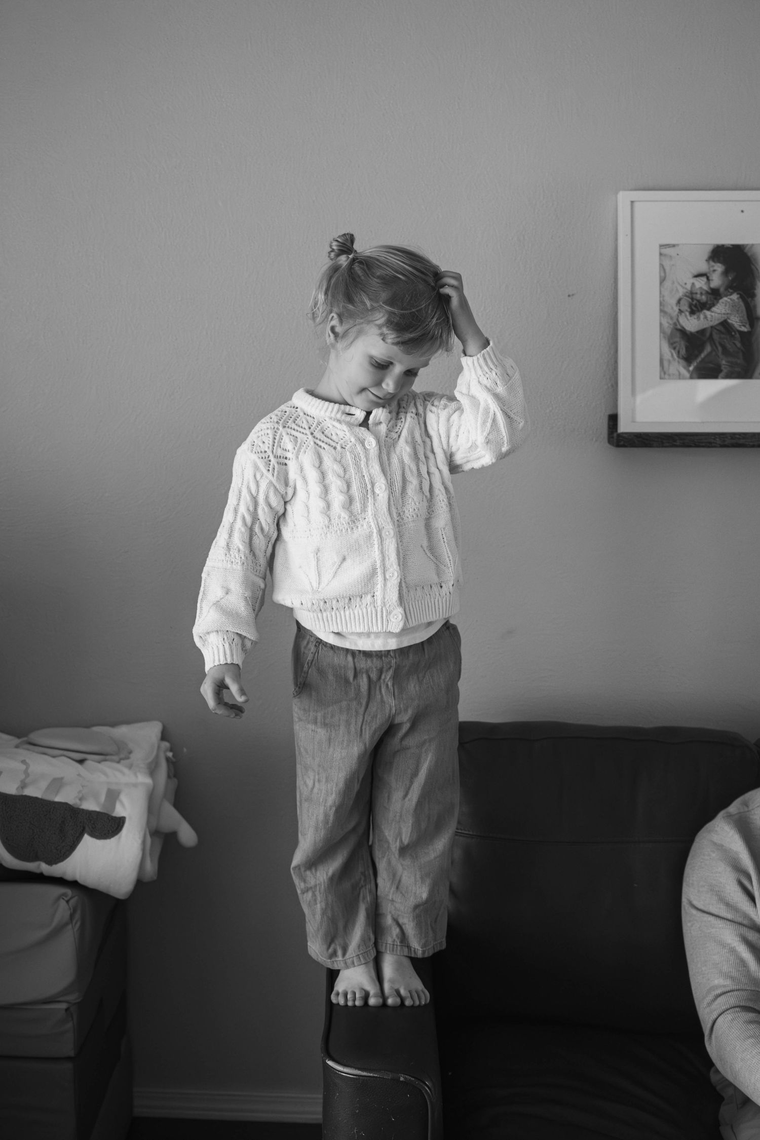 Young child standing on the couch arm during an in-home family photography session in Spokane, Washington.