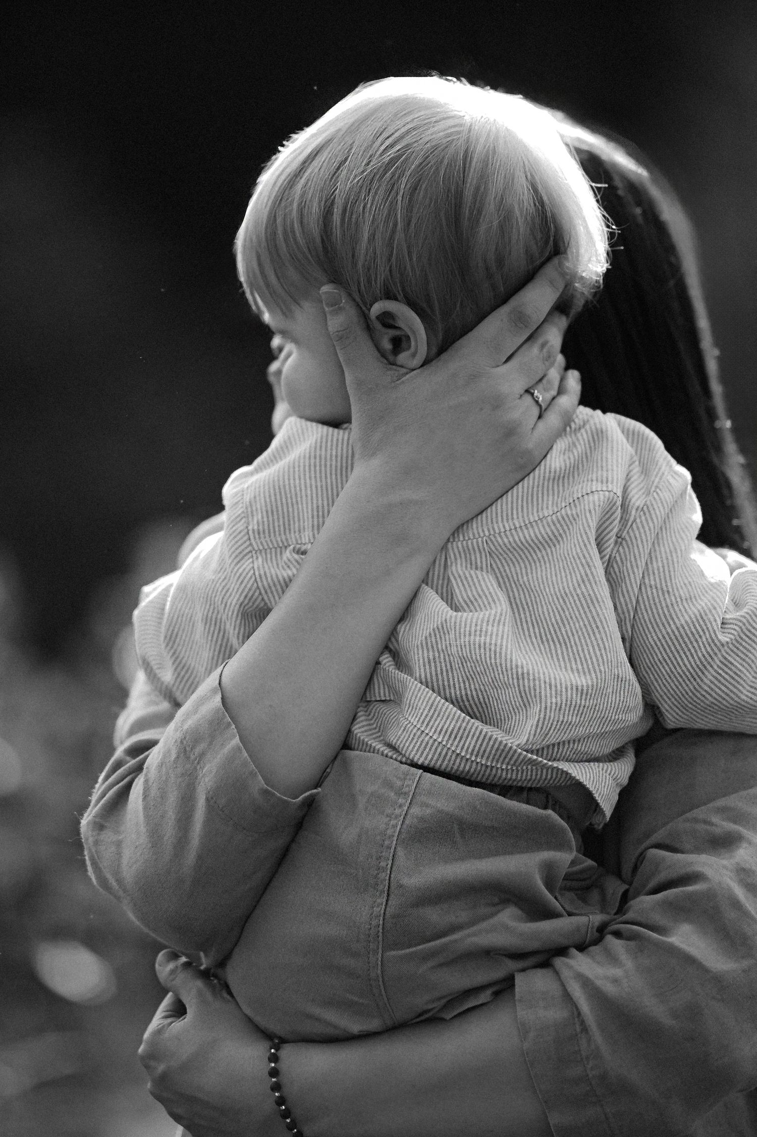 Black and white photo of a child being held and comforted by an adult, with a gentle hand cradling their face.
