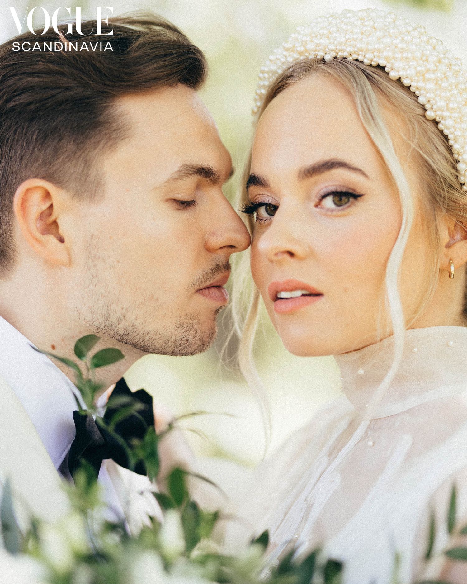 Romantic wedding couple closeup, bride wearing pearl headband and veil, groom in suit, featured in Vogue Scandinavia.