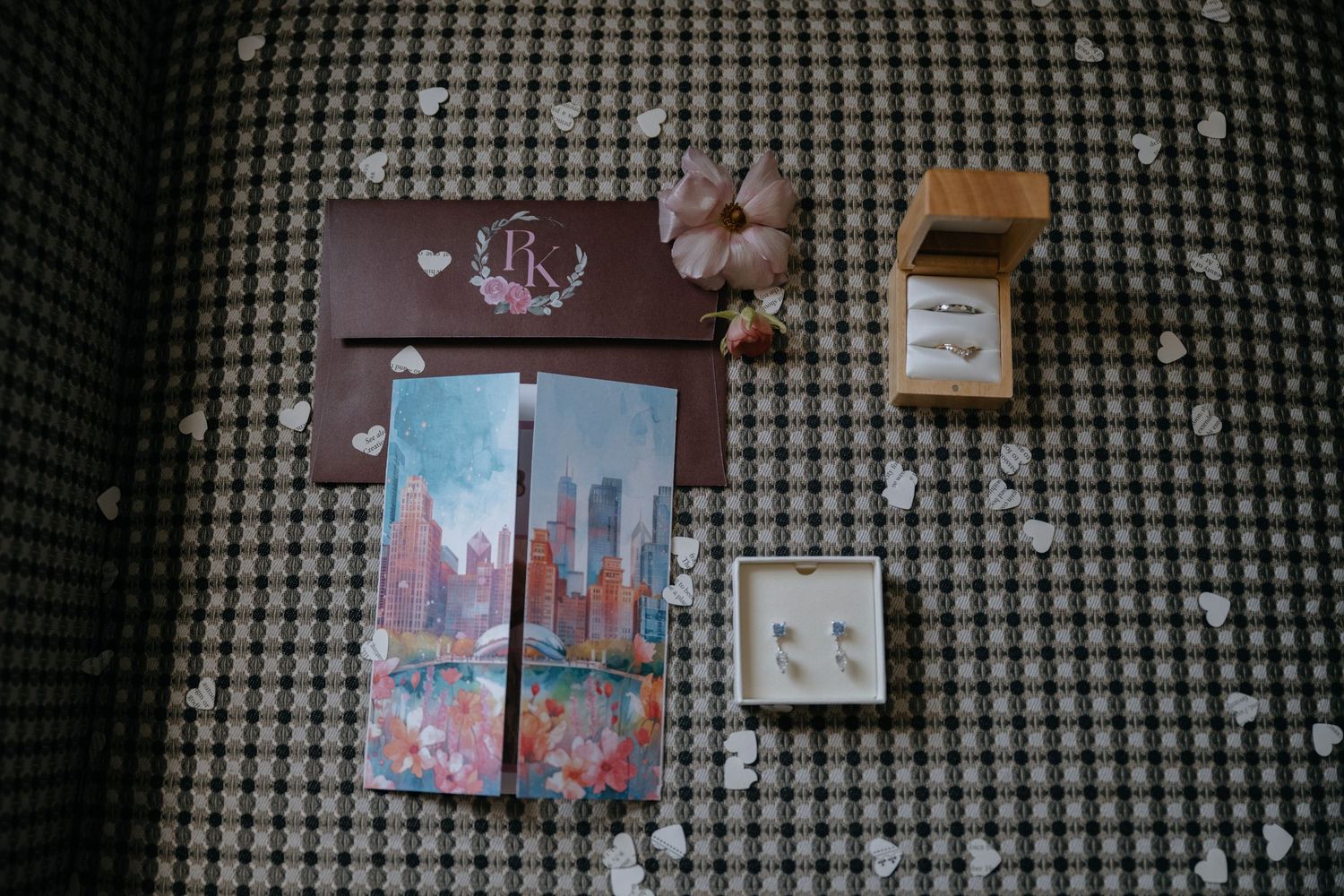 Flat lay of wedding details including monogrammed box, cityscape card, and pearl earrings.