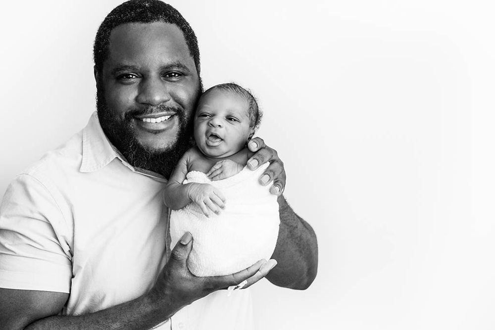 Black and white photo of dad and newborn baby boy in professional photography studio in Hemet California.