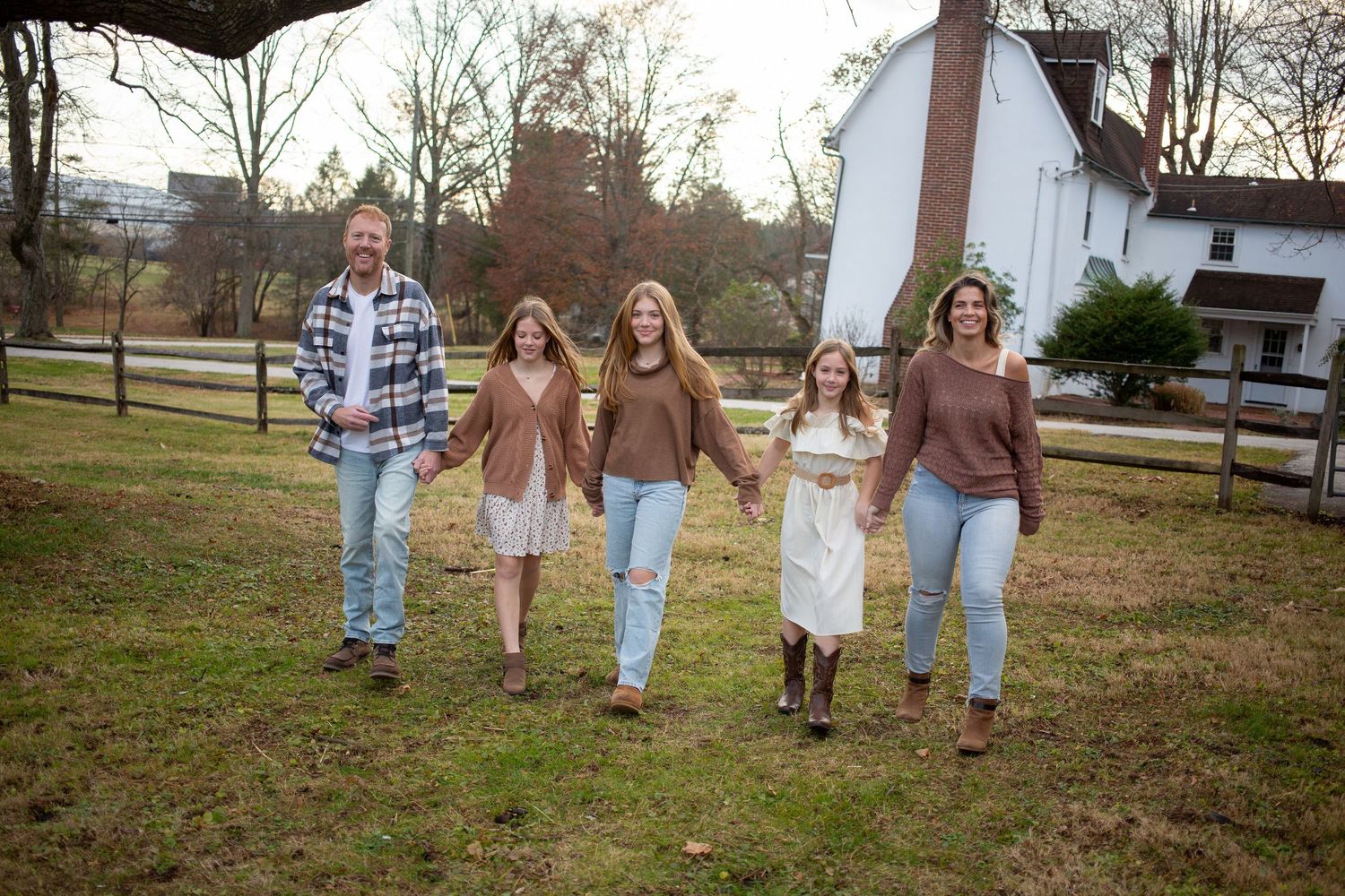 Family of six smiling together on a blanket in a lush green park on a sunny spring day.