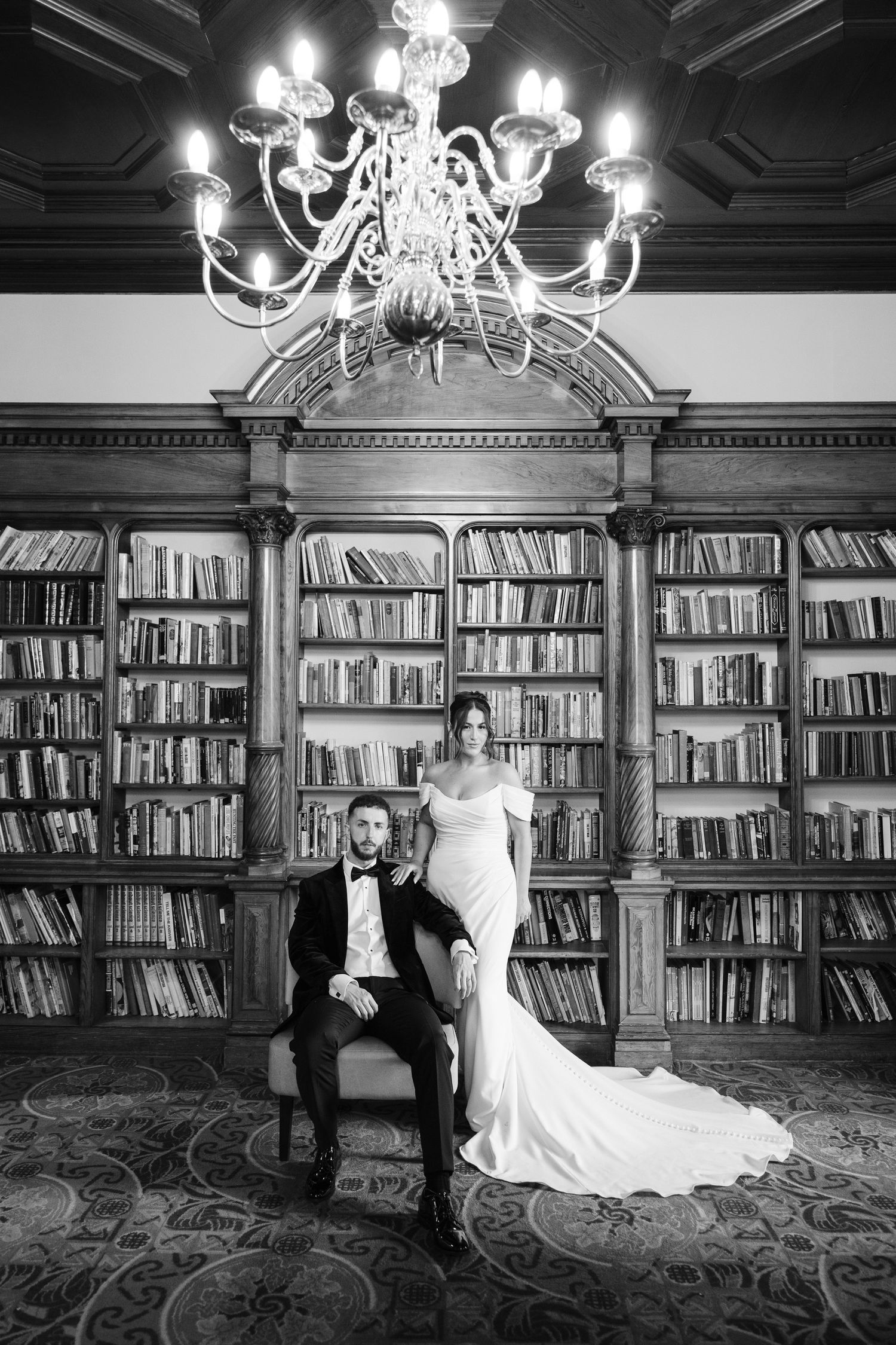 Black and white photo of a bride and groom toasting with champagne in an elegant restaurant venue.