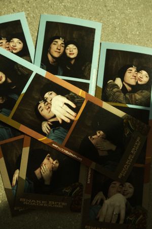 A collection of vintage photo booth strips arranged on a textured surface showing playful poses in dark lighting.