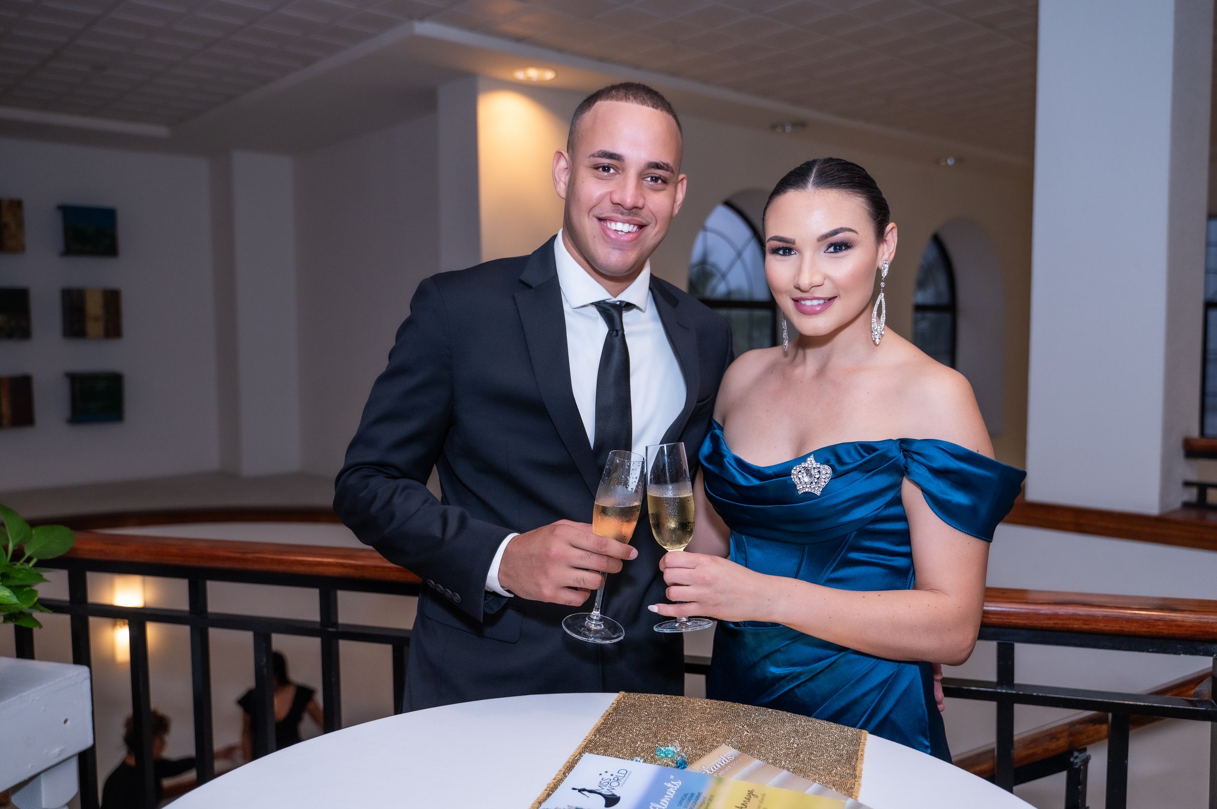Elegant couple in formal attire toasting with champagne glasses at an upscale event.