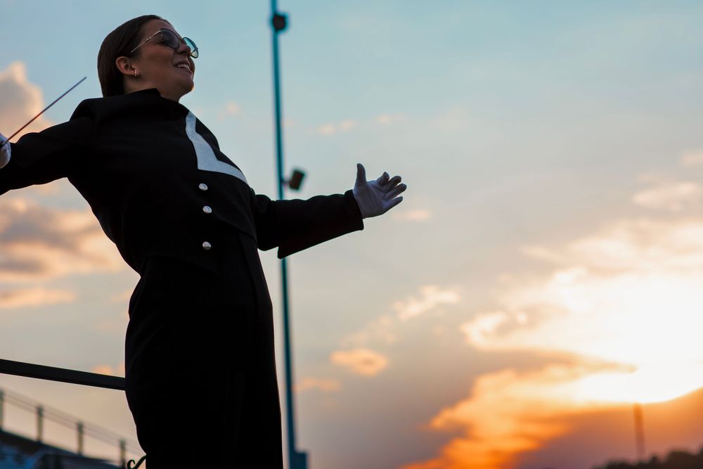 Silhouette of a conductor against a dramatic sunset sky.