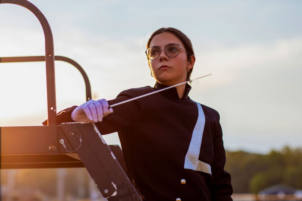 Band member in formal attire poses during golden hour on marching field.