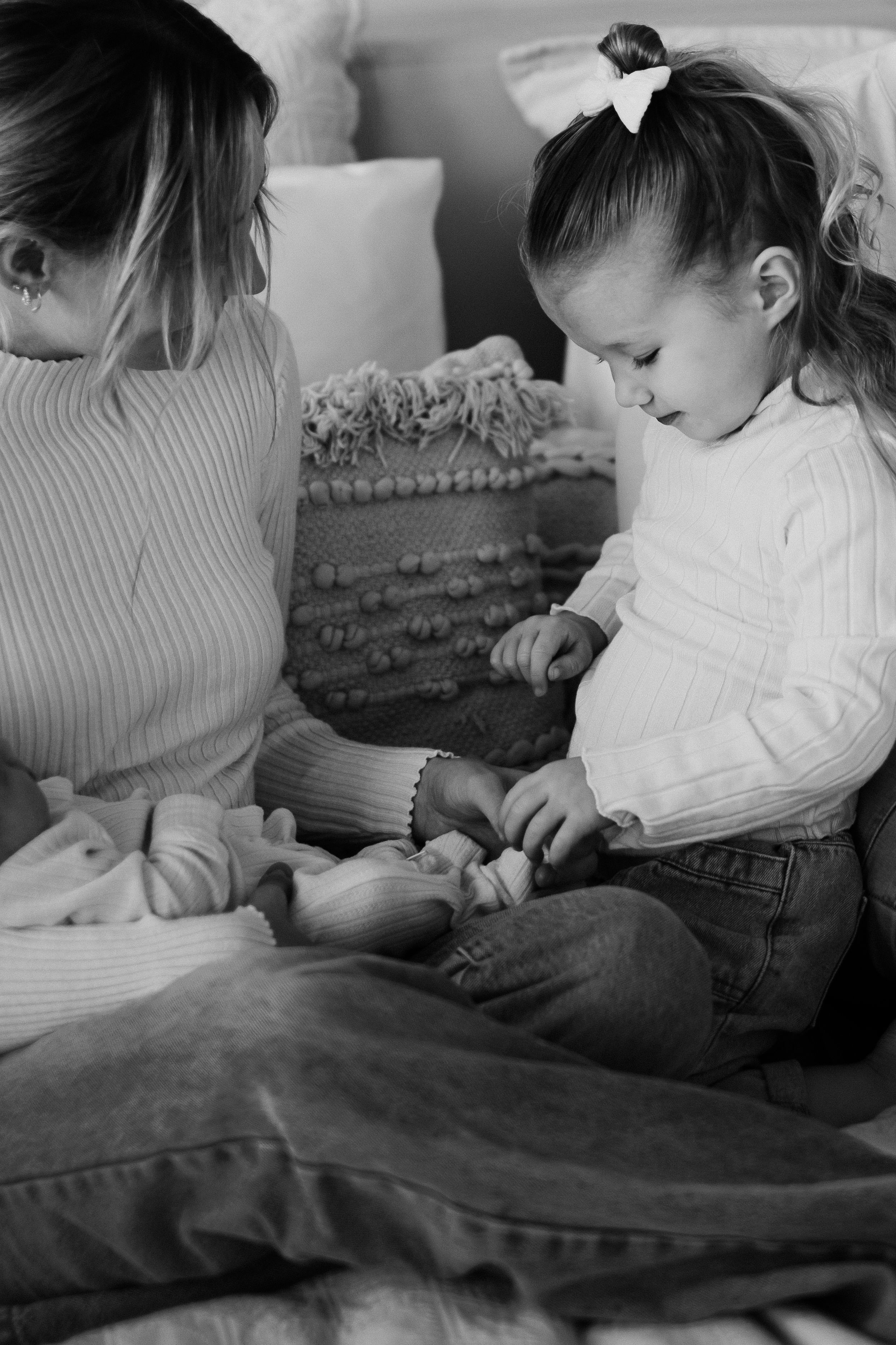 Black and white image of family sharing quiet moment on cozy bed.