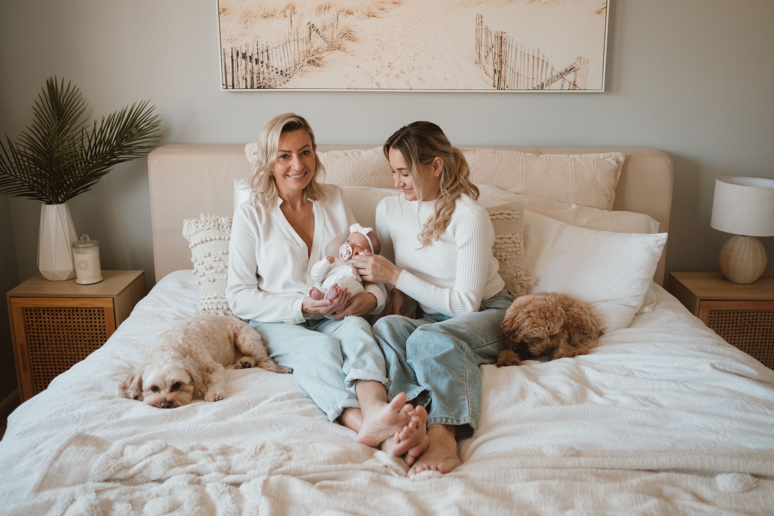 Relaxed family scene on bed with sleeping pets and neutral decor.