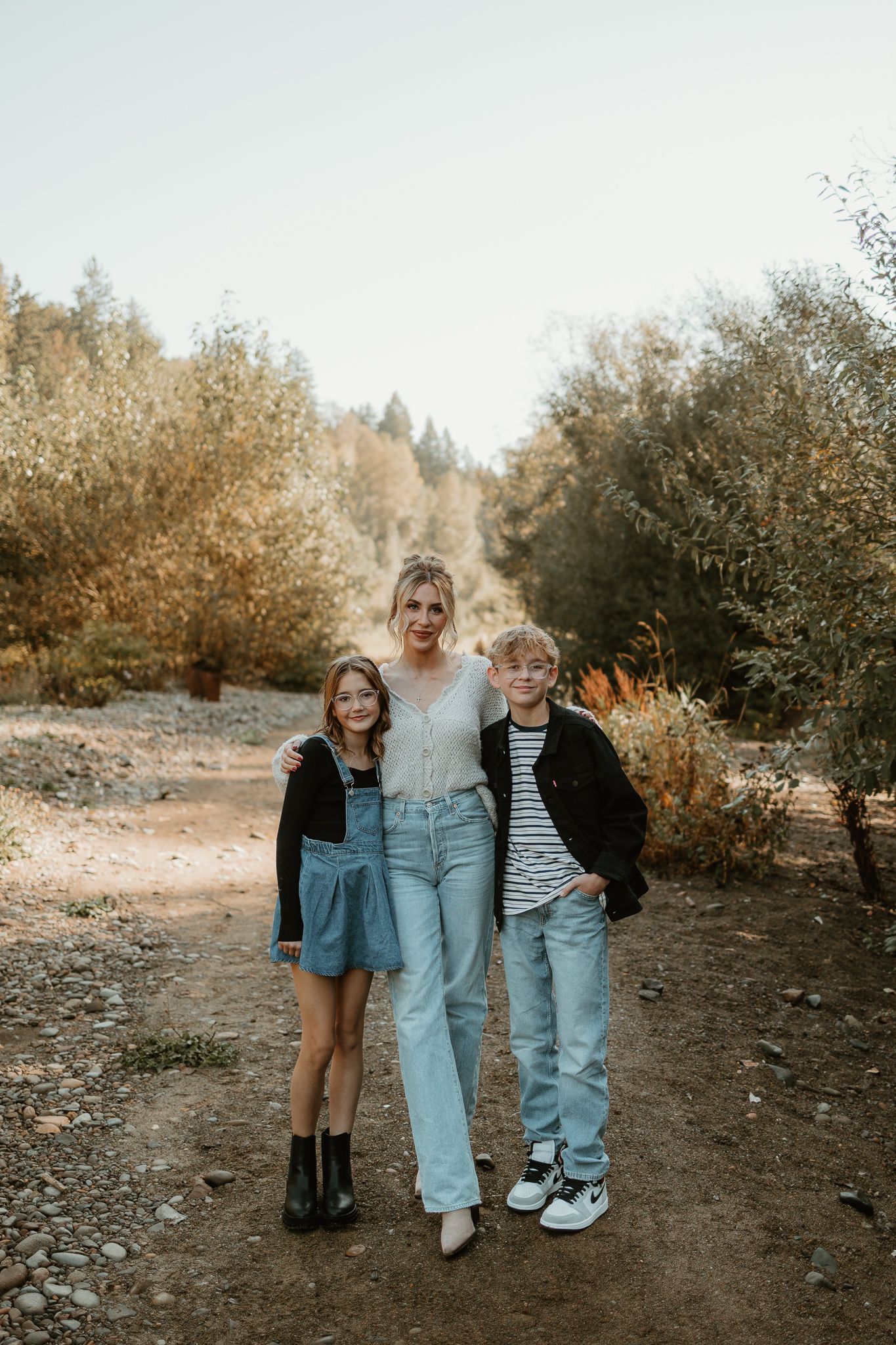 Three people standing together on an autumn trail with golden trees in the background.