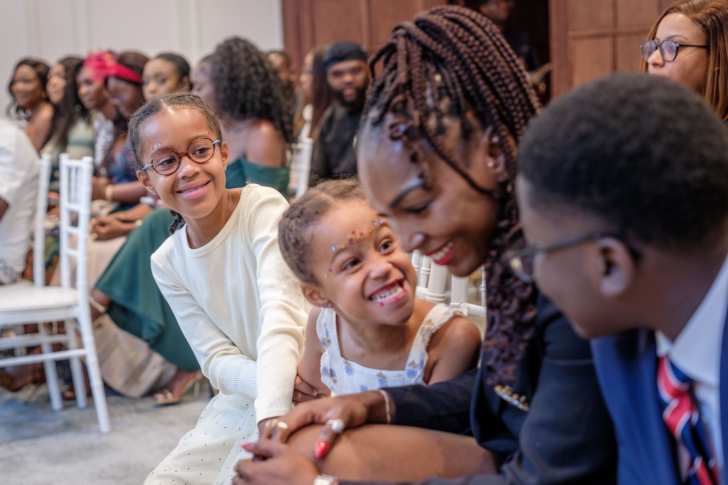 Children and adults share joyful smiles at a formal celebration event in an elegant venue.