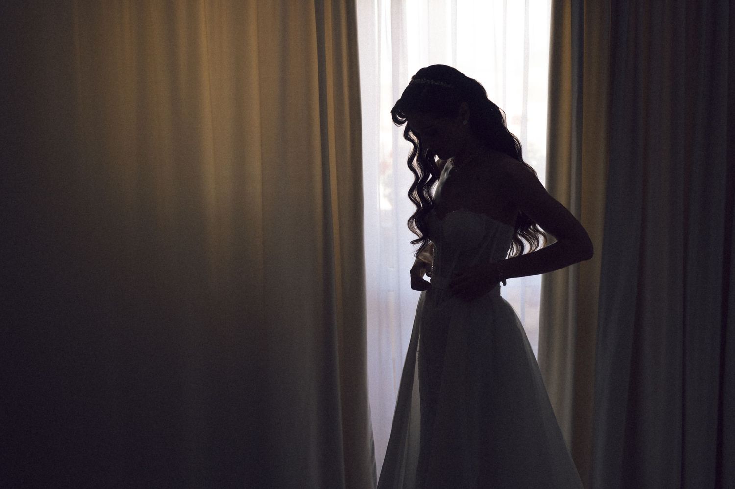 Silhouette of a woman in profile against a bright window, creating a dramatic contrast in lighting.