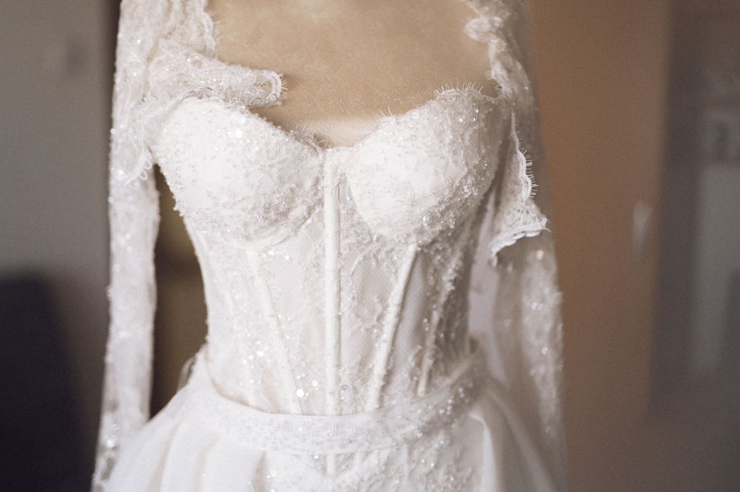 Close-up view of delicate white lace and beaded details on a wedding dress bodice.