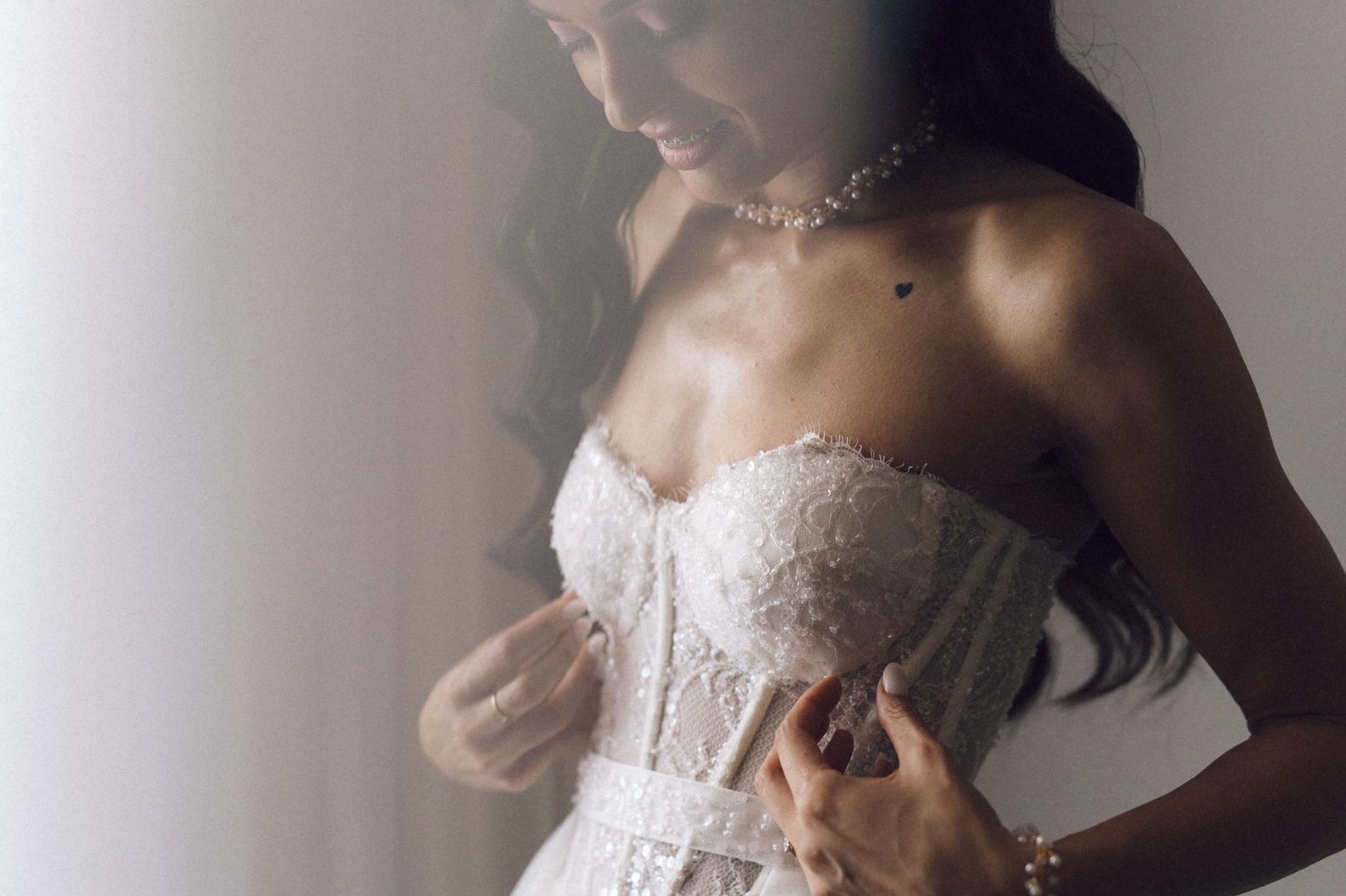 A bride in an elegant strapless lace wedding gown poses during a bridal photoshoot session.