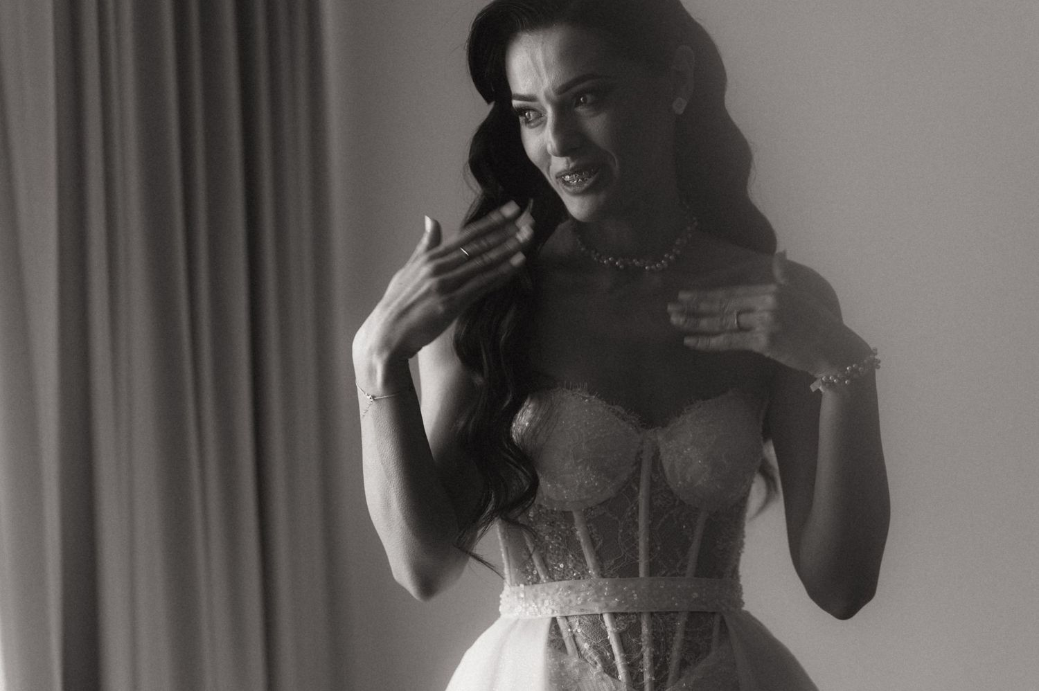 Black and white portrait of someone in a delicate lace corset top against a light background.