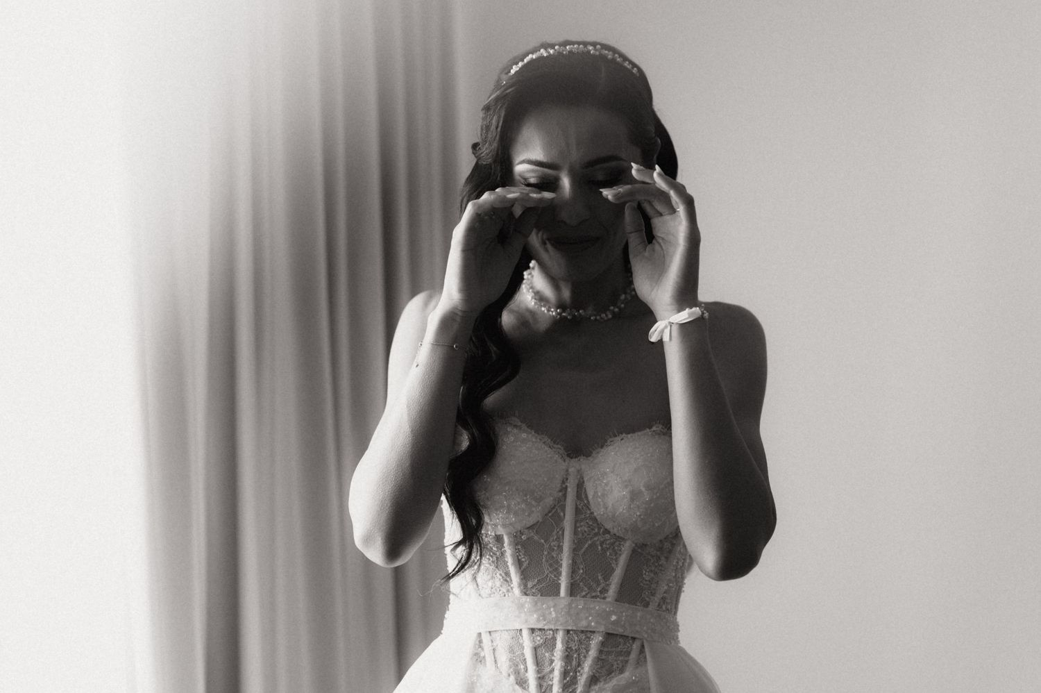 Monochrome fashion photograph showing a person wearing an elegant bustier style top in an intimate setting.