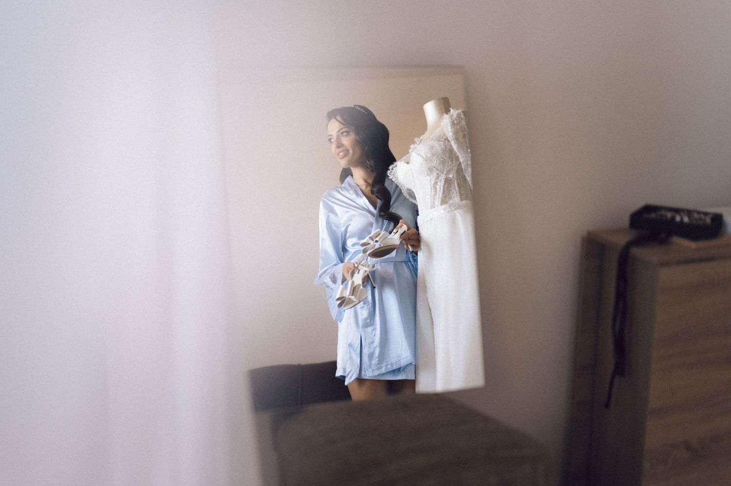 A person in a light blue top stands against a white wall in what appears to be a home interior.
