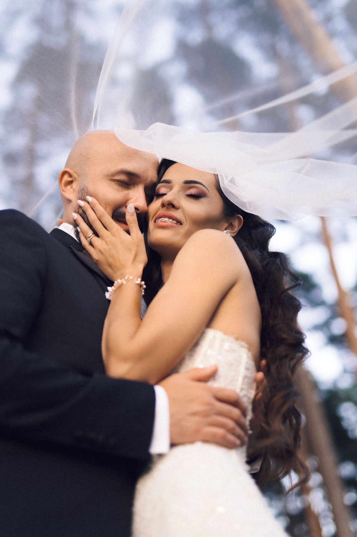 A romantic wedding couple embraces in an intimate dance pose against a soft blurred background.