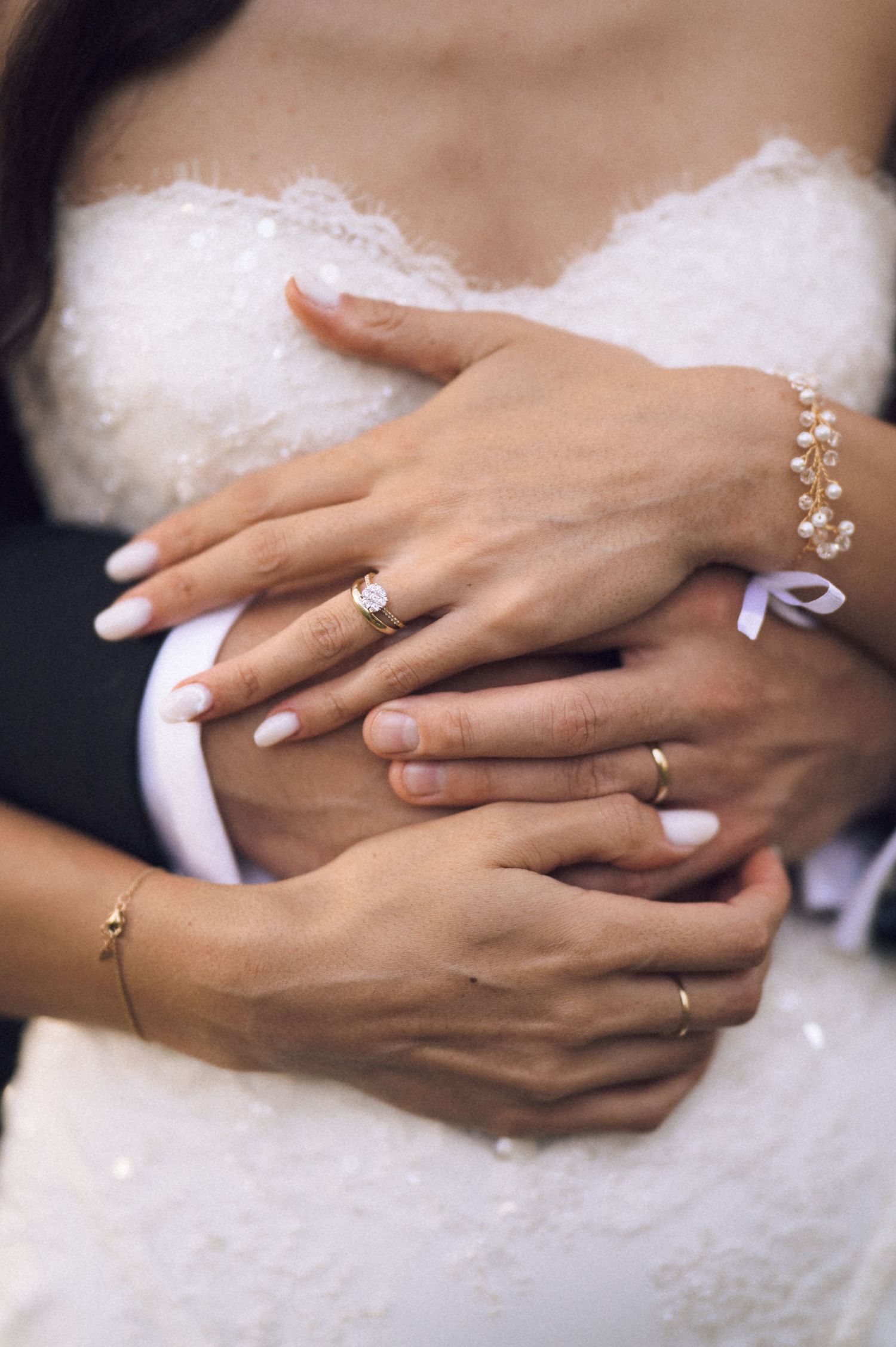A series of hands wearing elegant engagement rings resting on white fabric, showcasing different diamond solitaire styles.