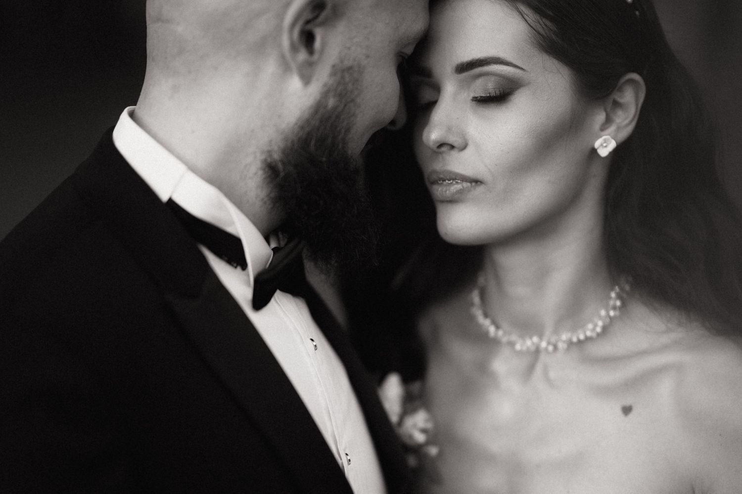 Romantic black and white wedding photo series showing intimate moments between bride and groom in formal attire.