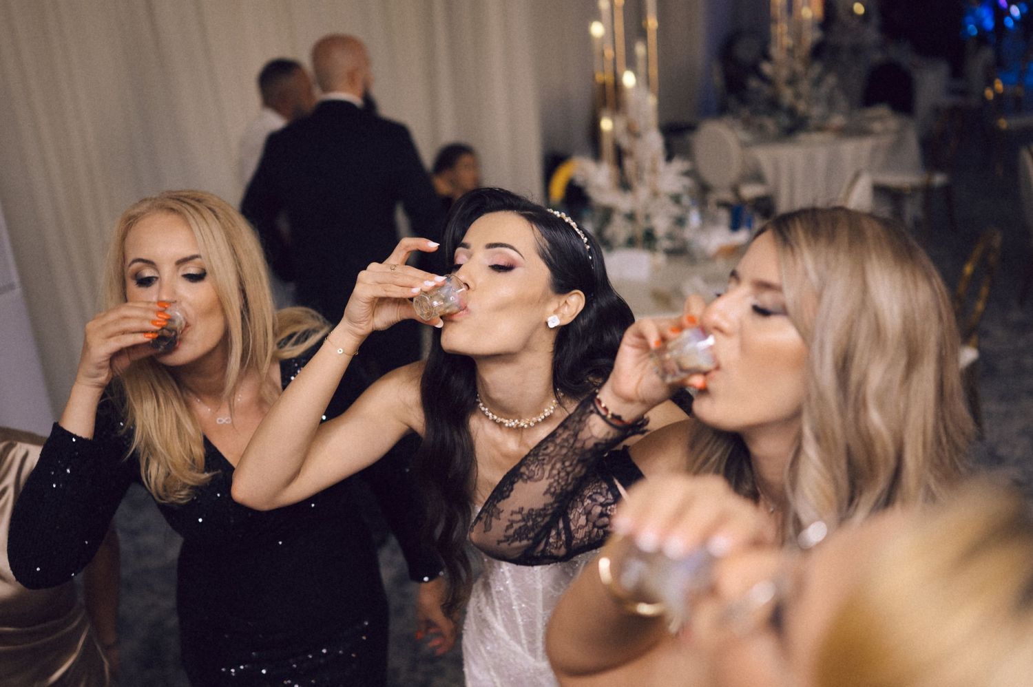 A group of party guests taking shots together at an event with dimmed lighting and festive atmosphere.