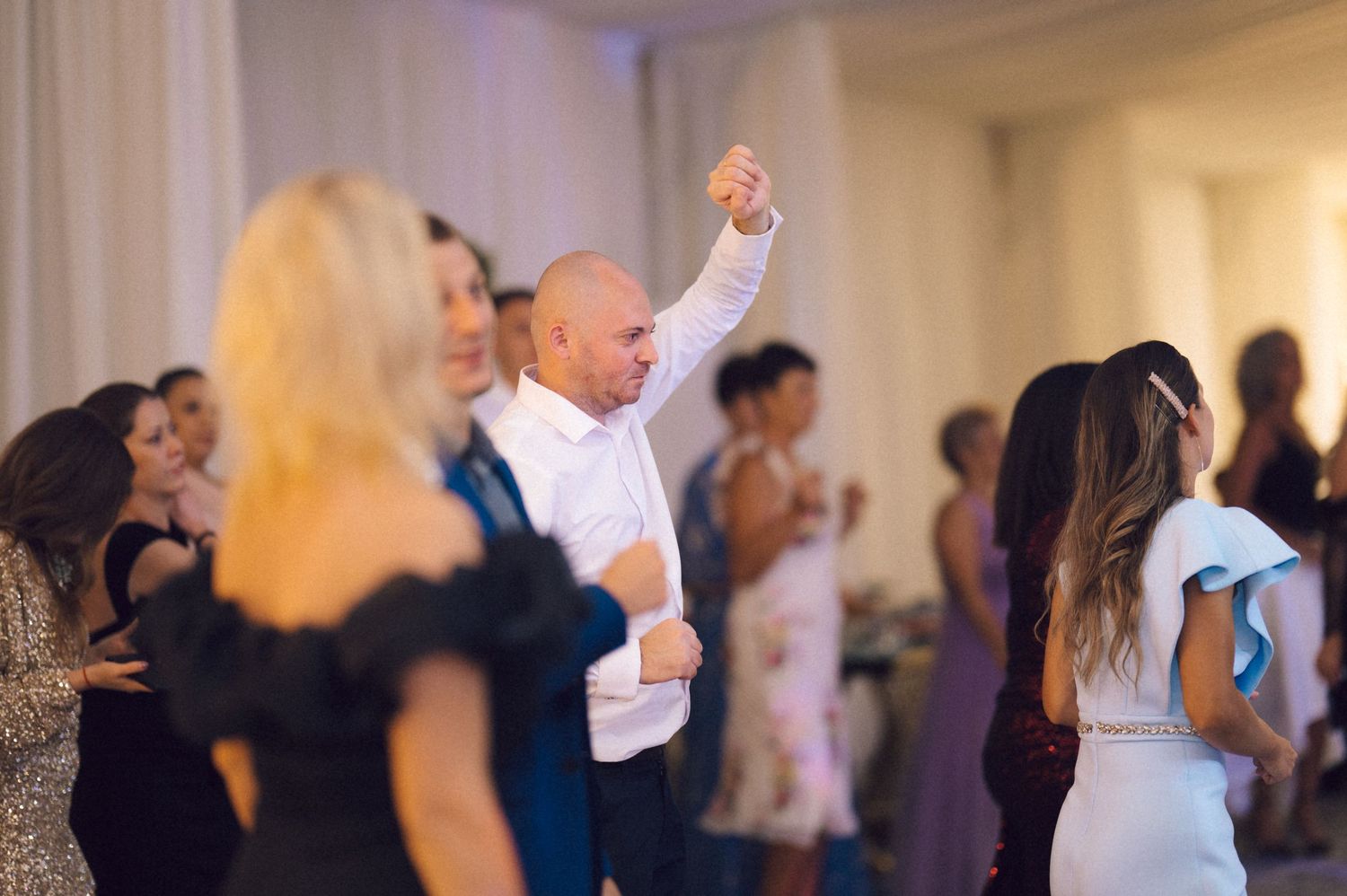 A group of people dancing together at a lively party or celebration in an indoor venue.
