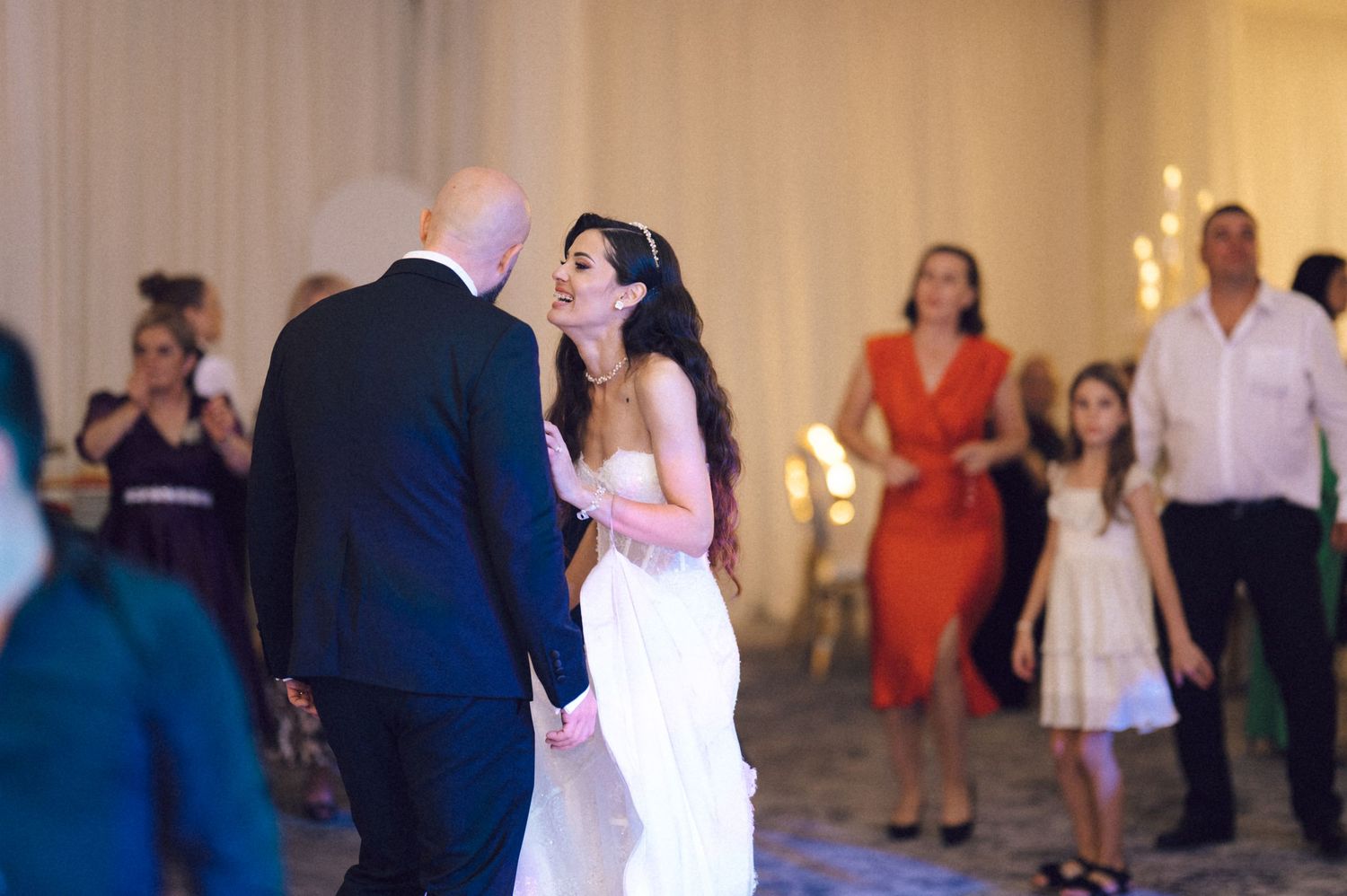 Couples dancing together at a wedding reception on a dimly lit dance floor.