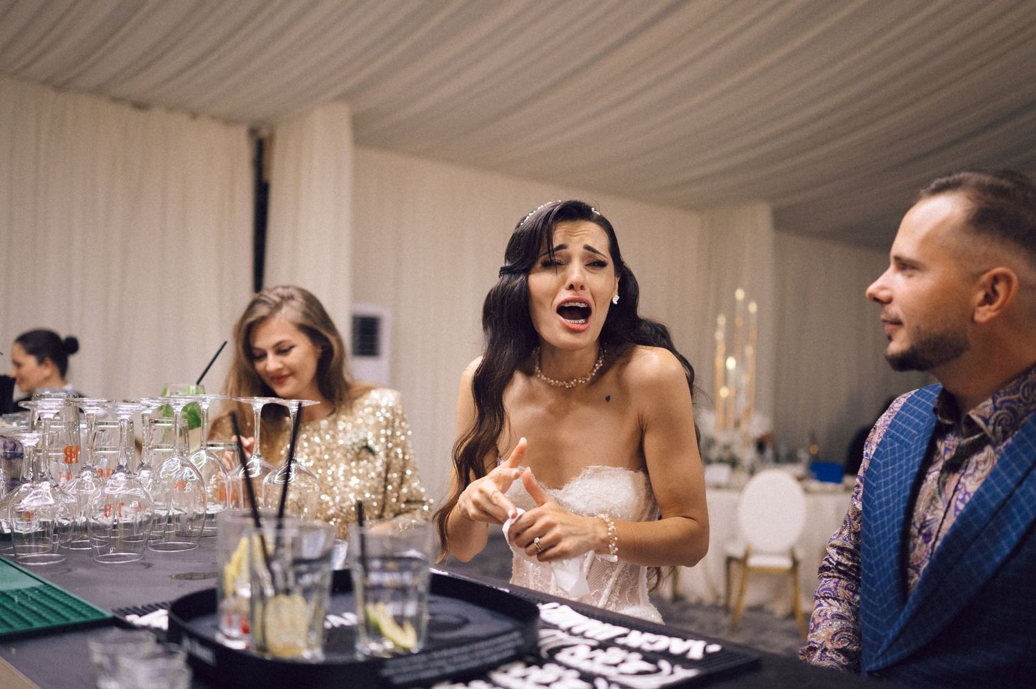 Candid moment of guests laughing and socializing at an elegant wedding reception bar area.