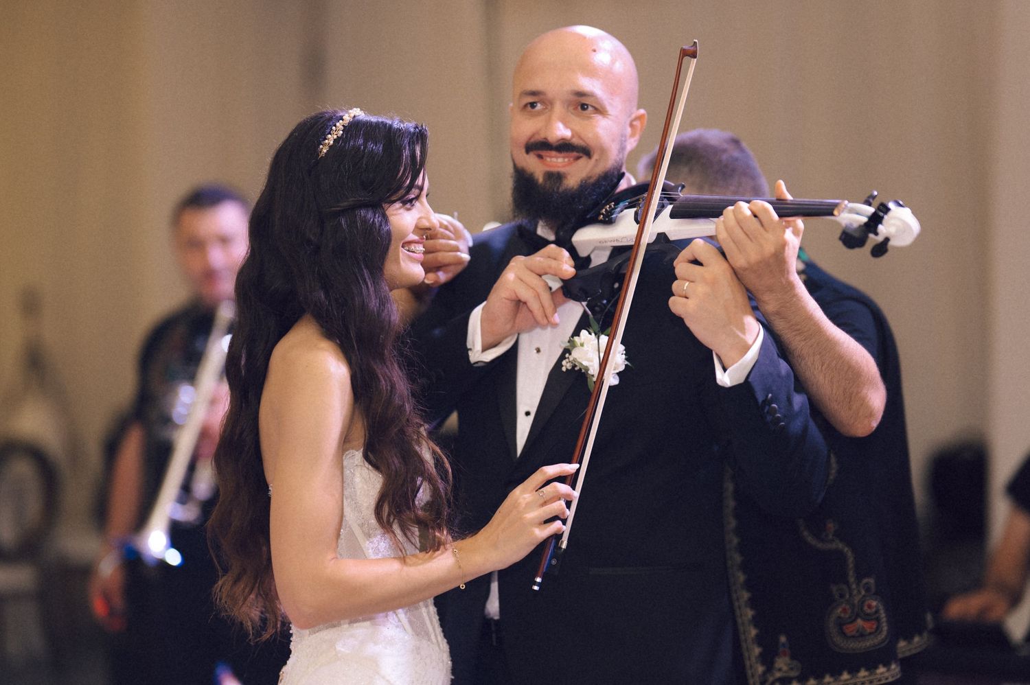 Musicians perform with violins during an elegant indoor event in formal attire.
