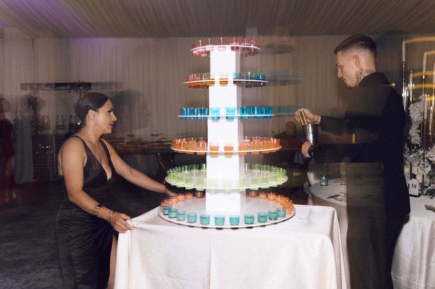 A multi-tiered blue and white champagne tower with glasses being filled at an elegant event reception.